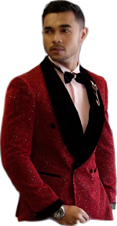 A man wearing a red sequined suit with a black velvet lapel stands in front of racks of suits and a mannequin wearing a navy suit
